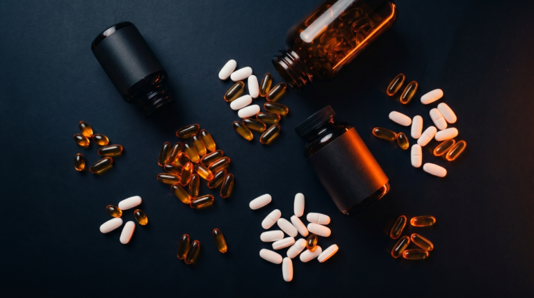 Frascos de multivitamínicos e cápsulas sobre fundo escuro com iluminação laranja neon